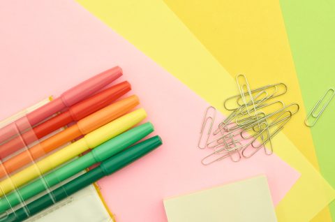 a rainbow table top with a few colorful markers and paper clips on top.
